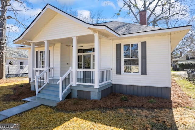 view of front of property with covered porch, a shingled roof, and a chimney