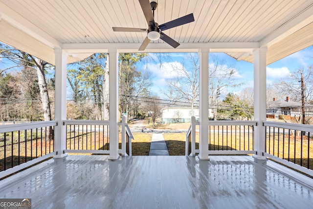 unfurnished sunroom featuring wooden ceiling, a ceiling fan, and a wealth of natural light