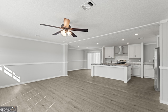 unfurnished living room with ornamental molding, visible vents, baseboards, and wood finished floors