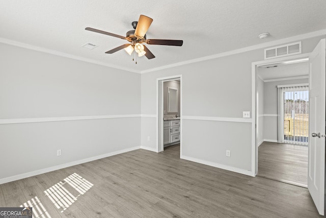 unfurnished bedroom featuring baseboards, visible vents, wood finished floors, a textured ceiling, and crown molding