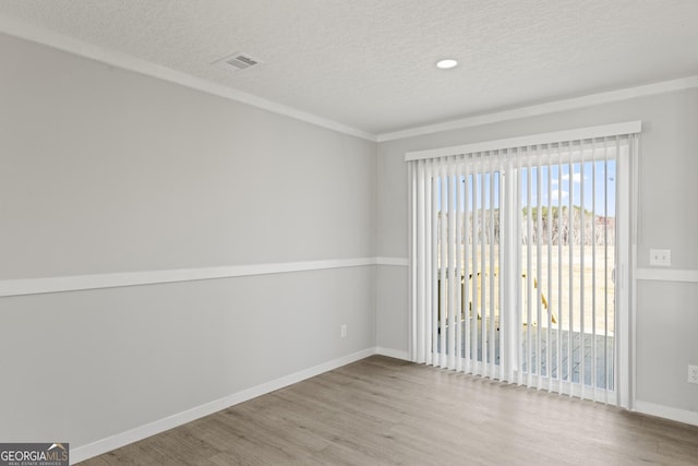 spare room with a textured ceiling, baseboards, and wood finished floors