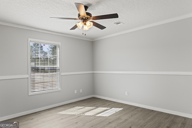 unfurnished room with baseboards, visible vents, ceiling fan, wood finished floors, and a textured ceiling