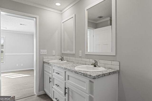 full bathroom with a textured ceiling, wood finished floors, a sink, and visible vents