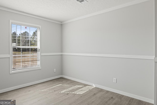 spare room featuring a textured ceiling, baseboards, and wood finished floors