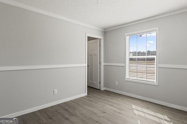 unfurnished room featuring a textured ceiling, wood finished floors, and baseboards