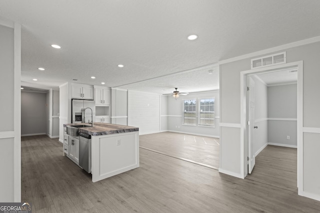 kitchen featuring wood finished floors, a sink, visible vents, and white cabinets