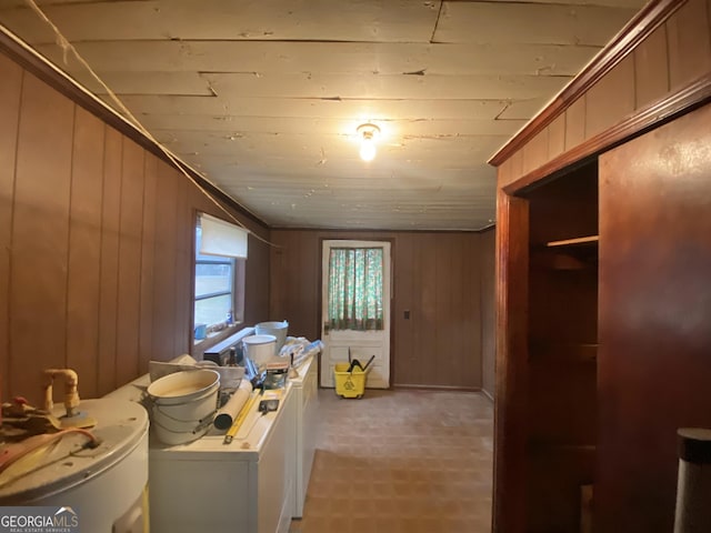 interior space with washing machine and dryer, water heater, and wood walls