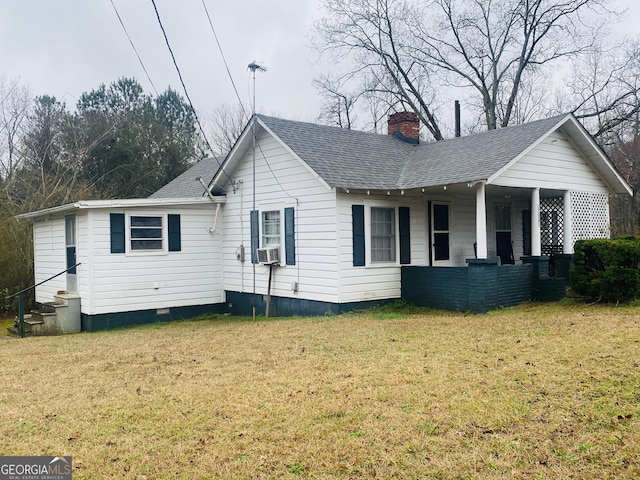 view of front facade with entry steps, covered porch, roof with shingles, a chimney, and a front yard