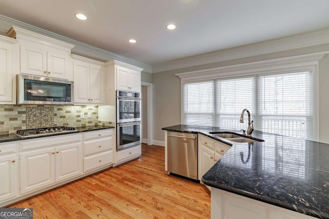 kitchen featuring crown molding, a wealth of natural light, appliances with stainless steel finishes, light wood-style floors, and a sink