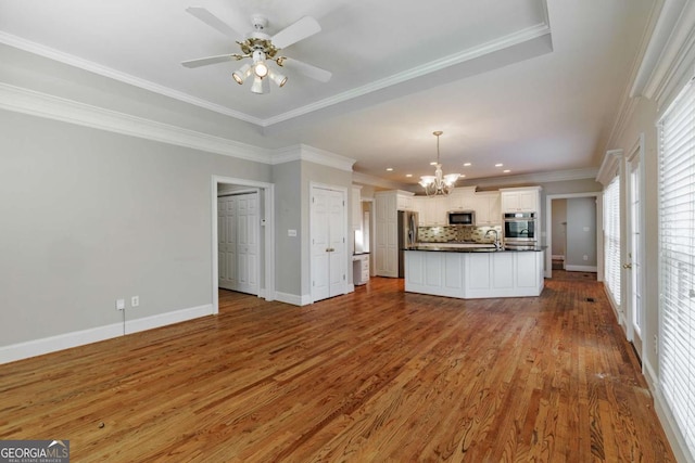 unfurnished living room with crown molding, a sink, baseboards, and wood finished floors