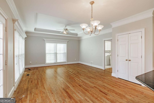 interior space featuring light wood-style floors, baseboards, a raised ceiling, and crown molding