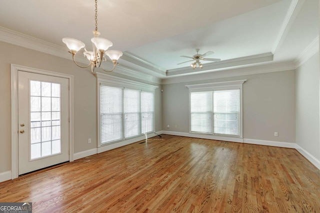 unfurnished room with ornamental molding, a tray ceiling, a healthy amount of sunlight, and light wood-style flooring