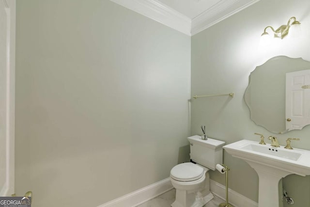 bathroom featuring baseboards, crown molding, a sink, and toilet