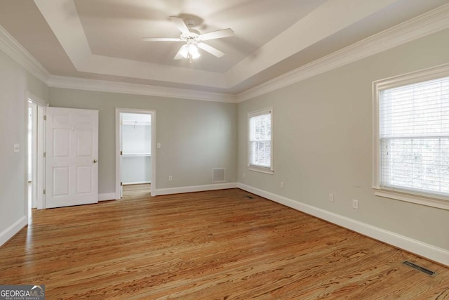 unfurnished room featuring light wood finished floors, visible vents, and a raised ceiling