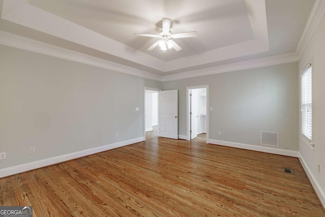 interior space featuring wood finished floors, a raised ceiling, and visible vents