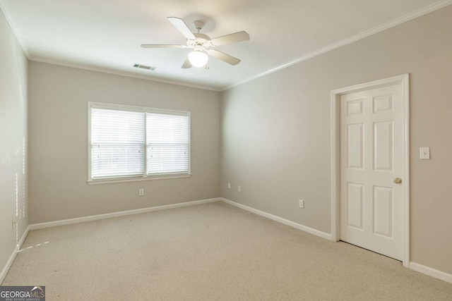 carpeted spare room with ornamental molding, visible vents, baseboards, and a ceiling fan