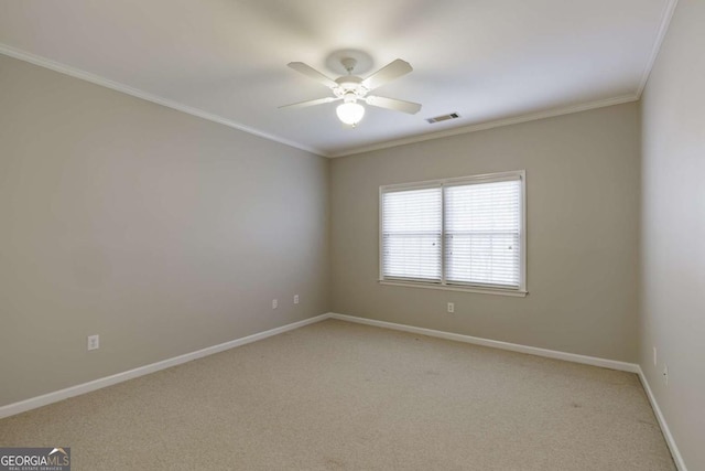 empty room featuring light colored carpet, visible vents, ornamental molding, a ceiling fan, and baseboards