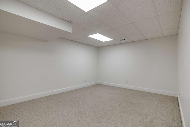 carpeted spare room featuring baseboards and a drop ceiling