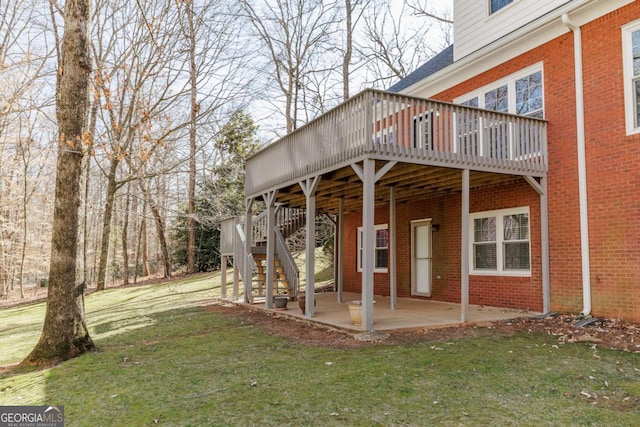 exterior space with a patio, brick siding, a lawn, stairway, and a wooden deck