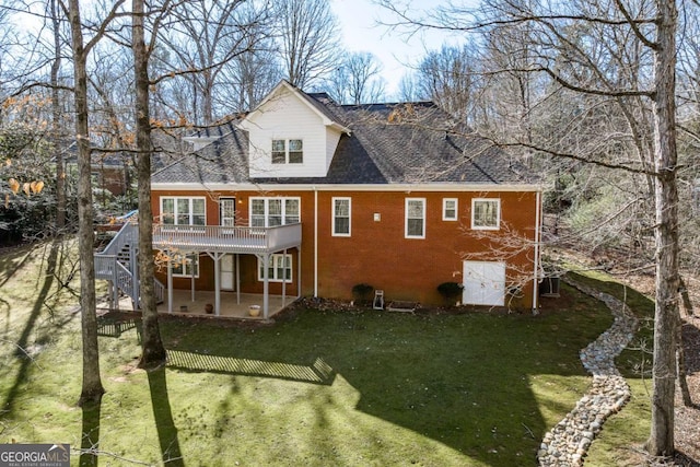 back of house with brick siding, a yard, a patio area, a deck, and stairs