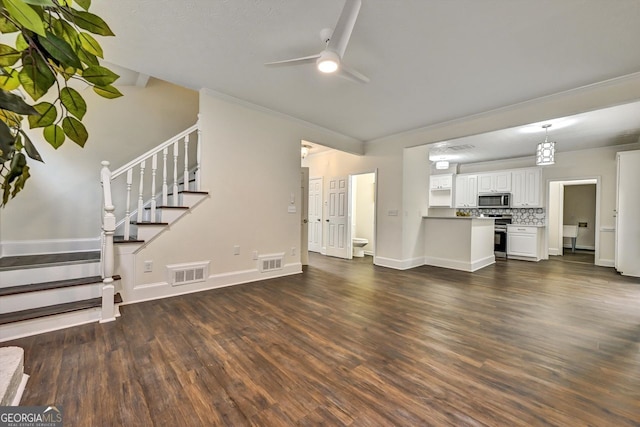 unfurnished living room featuring dark wood-style flooring, visible vents, ceiling fan, and stairway