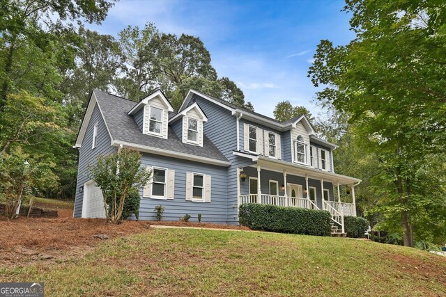 colonial house featuring a garage, a front yard, covered porch, and roof with shingles