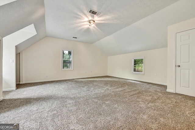 bonus room featuring carpet floors, visible vents, vaulted ceiling, and a textured ceiling