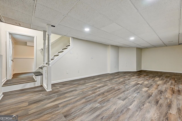 finished basement with a paneled ceiling, recessed lighting, wood finished floors, baseboards, and stairs