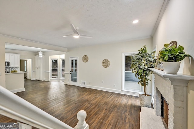 living room featuring visible vents, baseboards, ceiling fan, dark wood-type flooring, and a brick fireplace