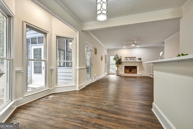 unfurnished living room featuring ornamental molding, dark wood finished floors, visible vents, and a fireplace with raised hearth