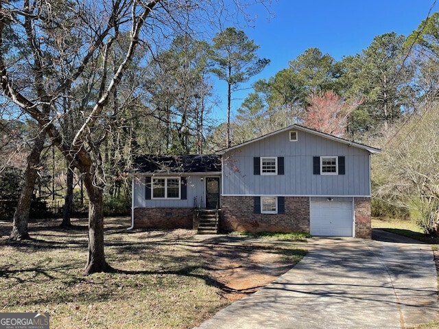 tri-level home featuring driveway, brick siding, and an attached garage