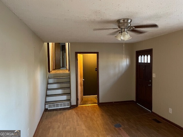 foyer featuring a textured ceiling, wood finished floors, visible vents, a ceiling fan, and stairway