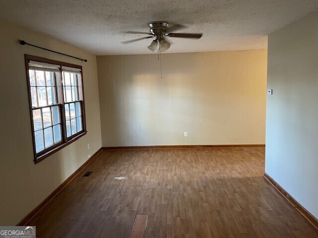 empty room with baseboards, a textured ceiling, visible vents, and wood finished floors