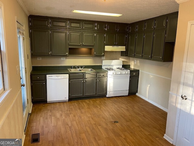 kitchen featuring dark countertops, visible vents, wood finished floors, white appliances, and under cabinet range hood