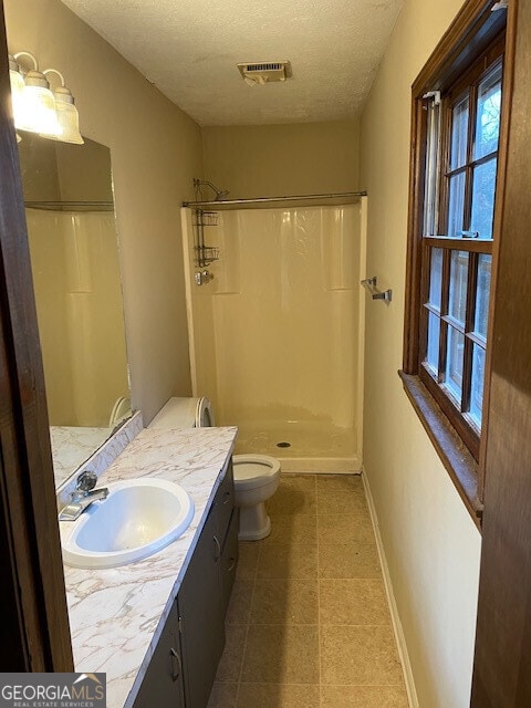 bathroom with visible vents, baseboards, a shower, and a textured ceiling