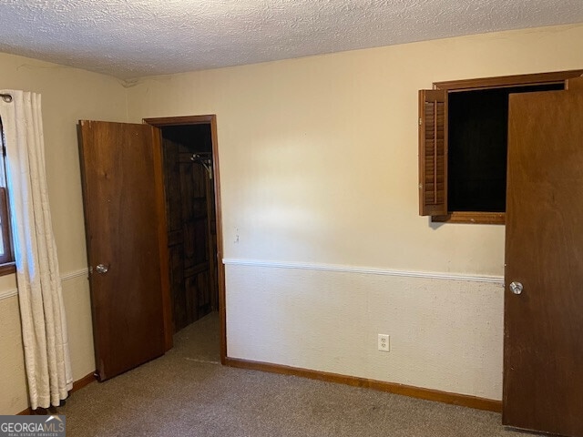 carpeted empty room with baseboards and a textured ceiling