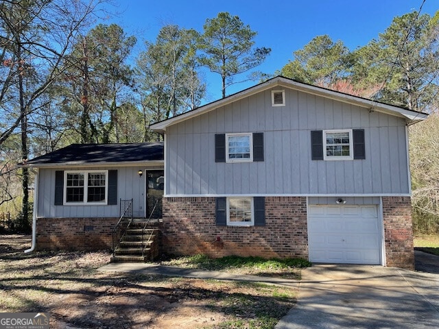 split level home with concrete driveway, brick siding, crawl space, and an attached garage