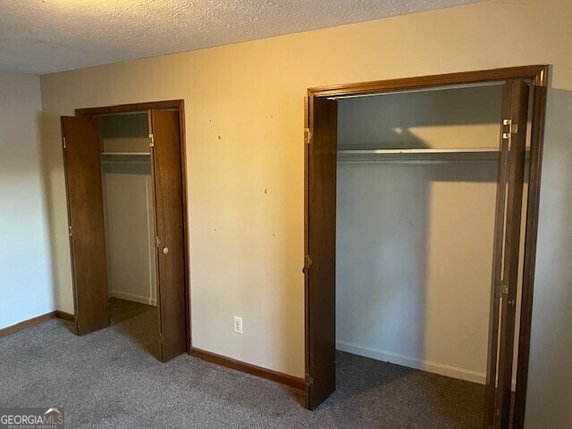 unfurnished bedroom with a textured ceiling, carpet floors, and baseboards