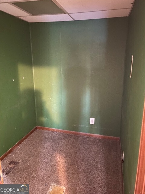 spare room featuring a paneled ceiling and baseboards