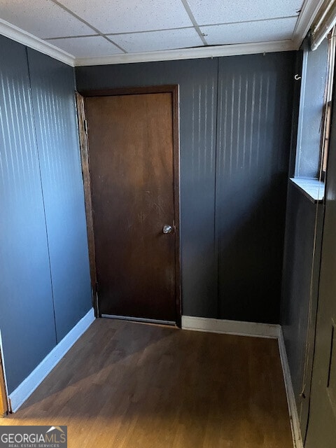 interior space with a paneled ceiling, baseboards, and wood finished floors