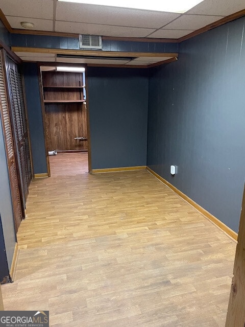 finished basement with a drop ceiling, light wood-type flooring, visible vents, and baseboards