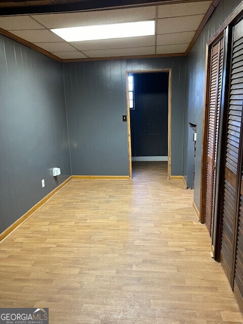 unfurnished room featuring light wood-type flooring, a paneled ceiling, and baseboards