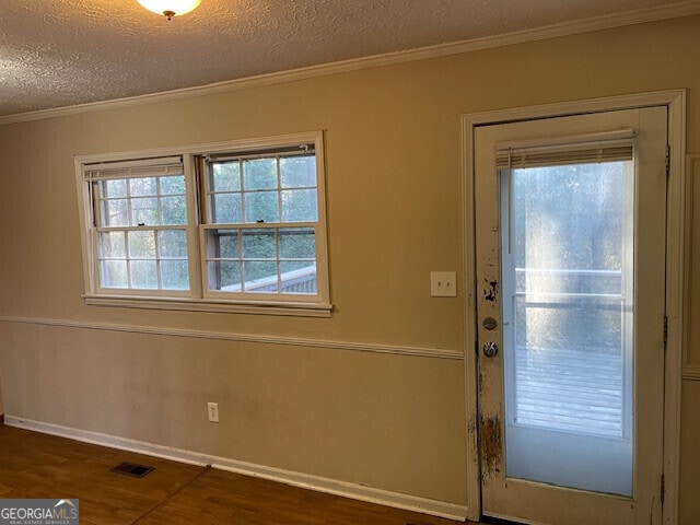 doorway with dark wood-style floors, crown molding, visible vents, and a textured ceiling