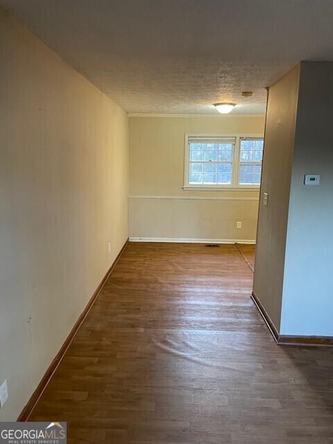 spare room featuring baseboards and wood finished floors