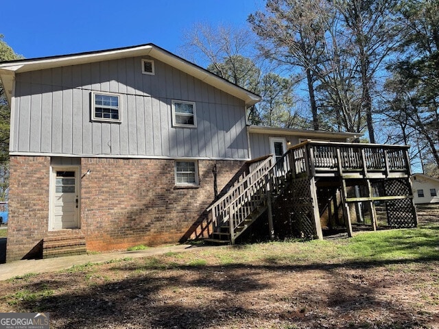 back of house with a wooden deck, stairway, and brick siding