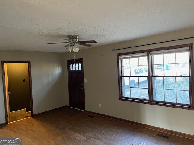 entryway with a textured ceiling, wood finished floors, visible vents, and baseboards