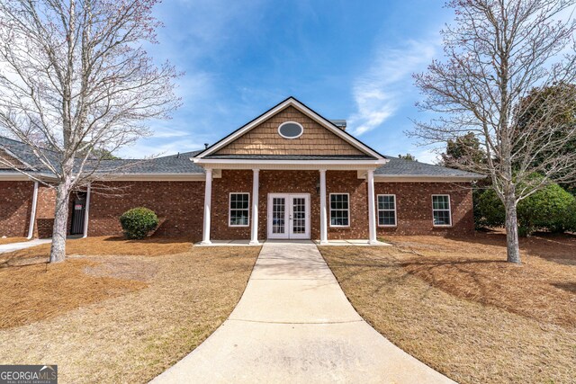 view of front of home featuring french doors, brick siding, and roof with shingles