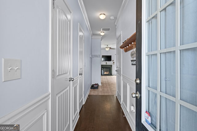 hall featuring a decorative wall, a wainscoted wall, visible vents, dark wood finished floors, and crown molding