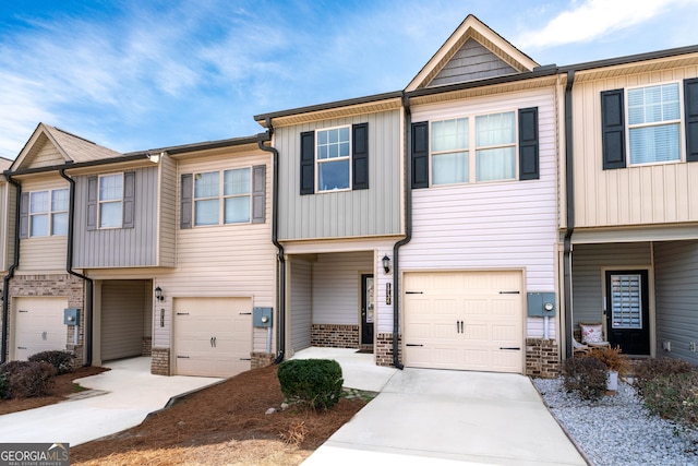 townhome / multi-family property featuring an attached garage, concrete driveway, and brick siding