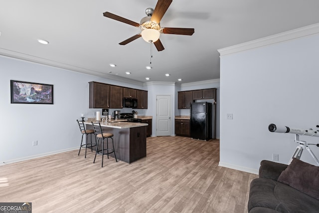 kitchen featuring a breakfast bar, open floor plan, dark brown cabinetry, a peninsula, and black appliances